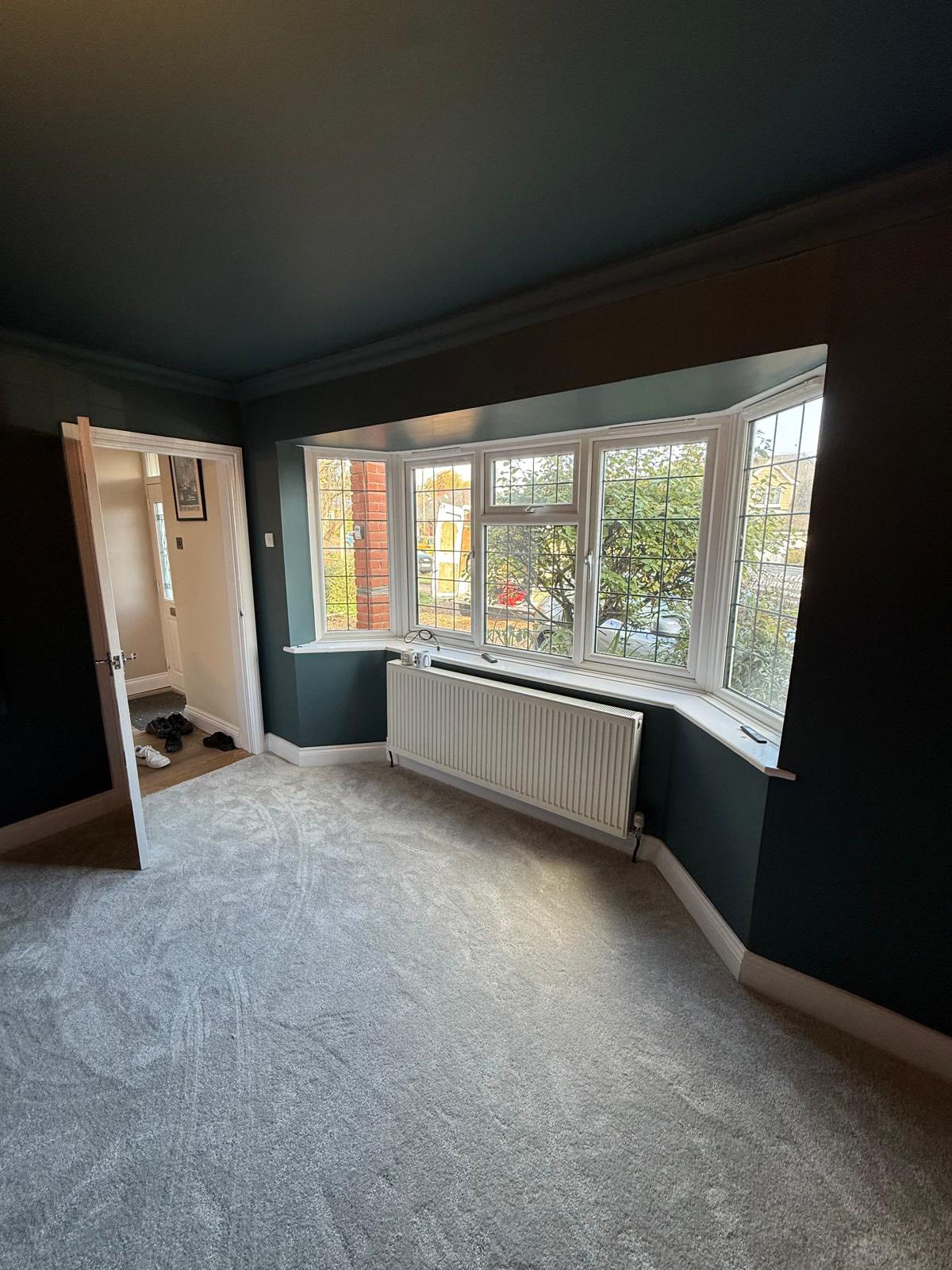 Room with dark teal walls and bay windows